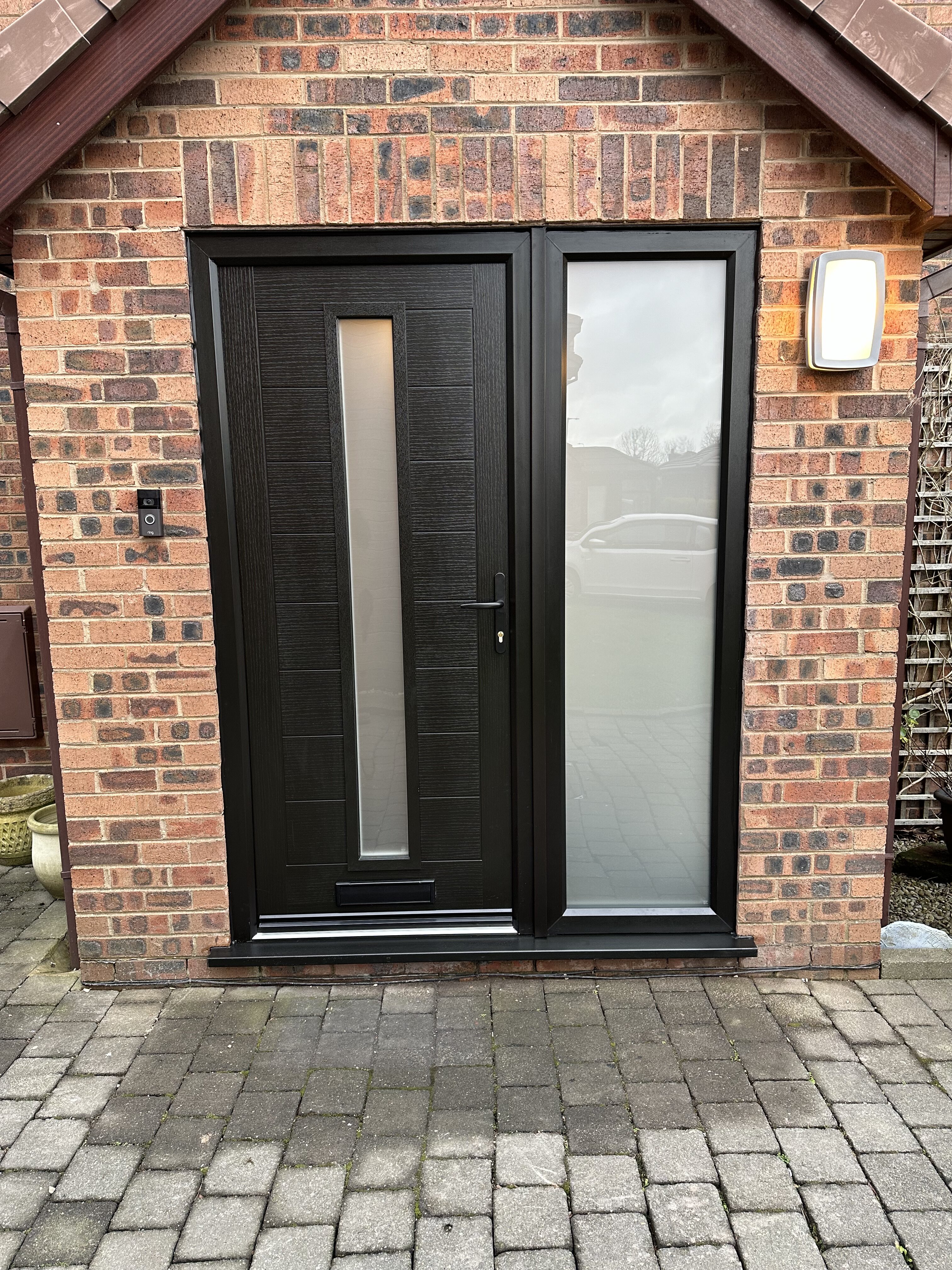 All black modern front composite door and side frame with black hardware and satin privacy glass